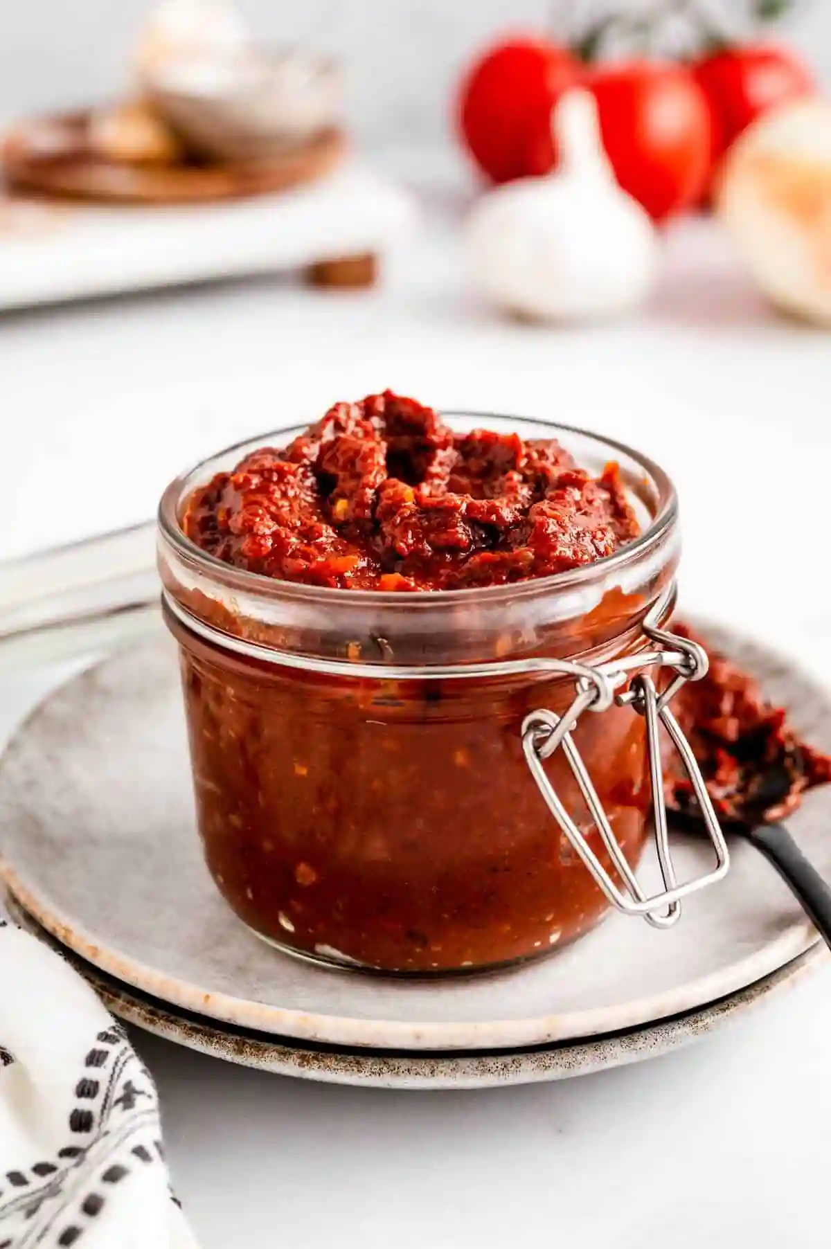 Hello Fresh Tex Mex Paste 4 Glass jar of thick homemade Tex Mex Paste on a ceramic plate, surrounded by tomatoes, garlic, and a spoonful of paste