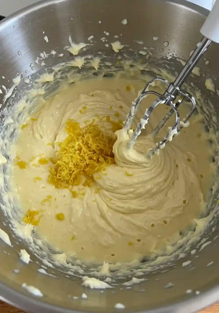 Mixing lemon juice and zest into fluffy cake batter in a stand mixer