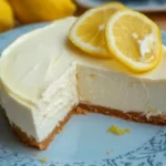 Whole no bake lemon cheesecake topped with lemon zest, on a white plate