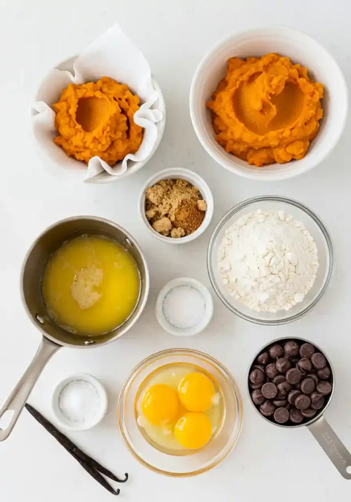 Ingredients for pumpkin chocolate chip cookies including flour, brown butter, pumpkin puree, chocolate chips and spices