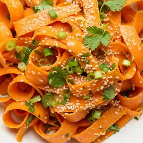 Viral Raw Carrot Salad with ribboned carrots, sesame seeds, and green onions in Asian dressing