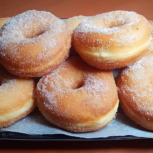 Golden homemade fluffy doughnuts with glossy glaze arranged on white plate showing perfect pillowy texture
