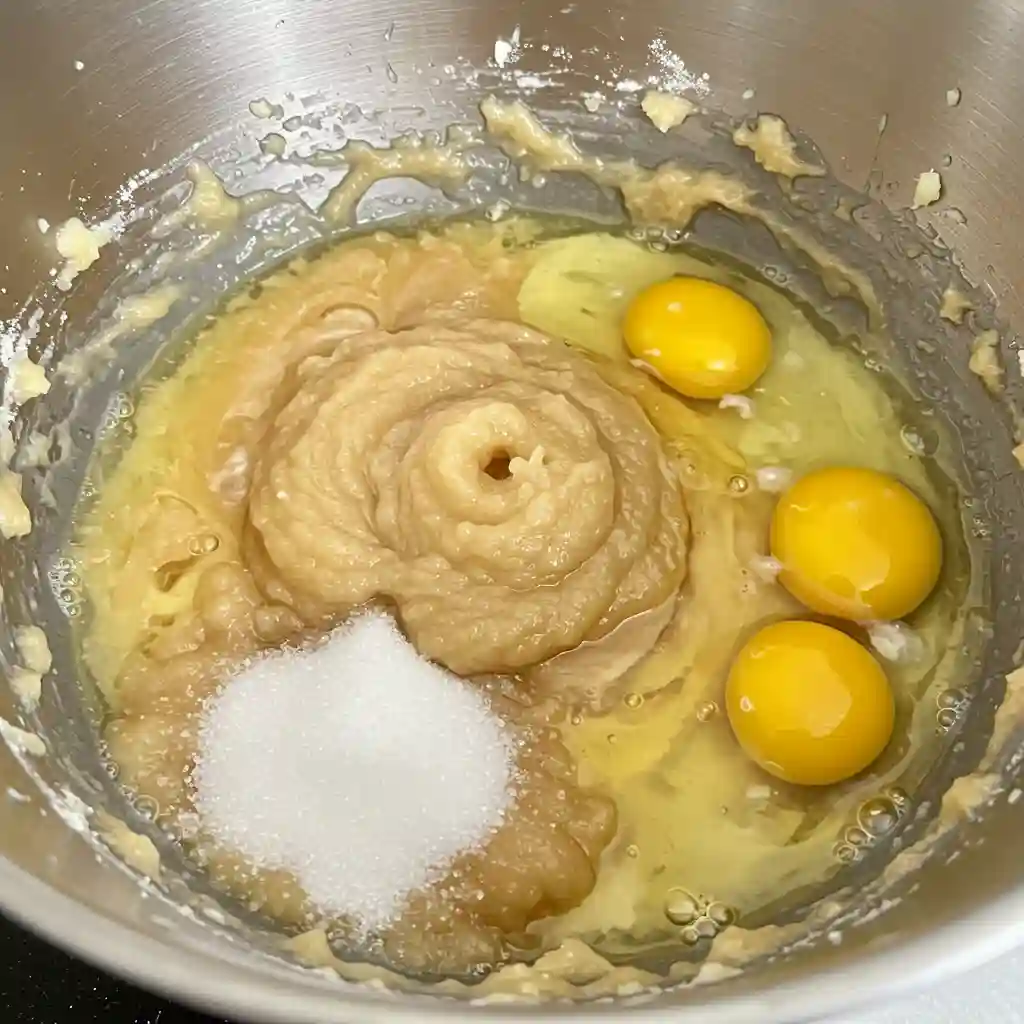 Mixing bowl with combined wet ingredients for blueberry zucchini bread including oil, eggs, sugar, and vanilla