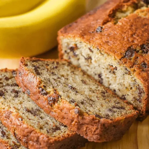 The Ultimate Moist Banana Bread Recipe Delicious, freshly baked banana bread, sliced on a wooden board with ripe bananas, showcasing a tempting banana bread recipe.