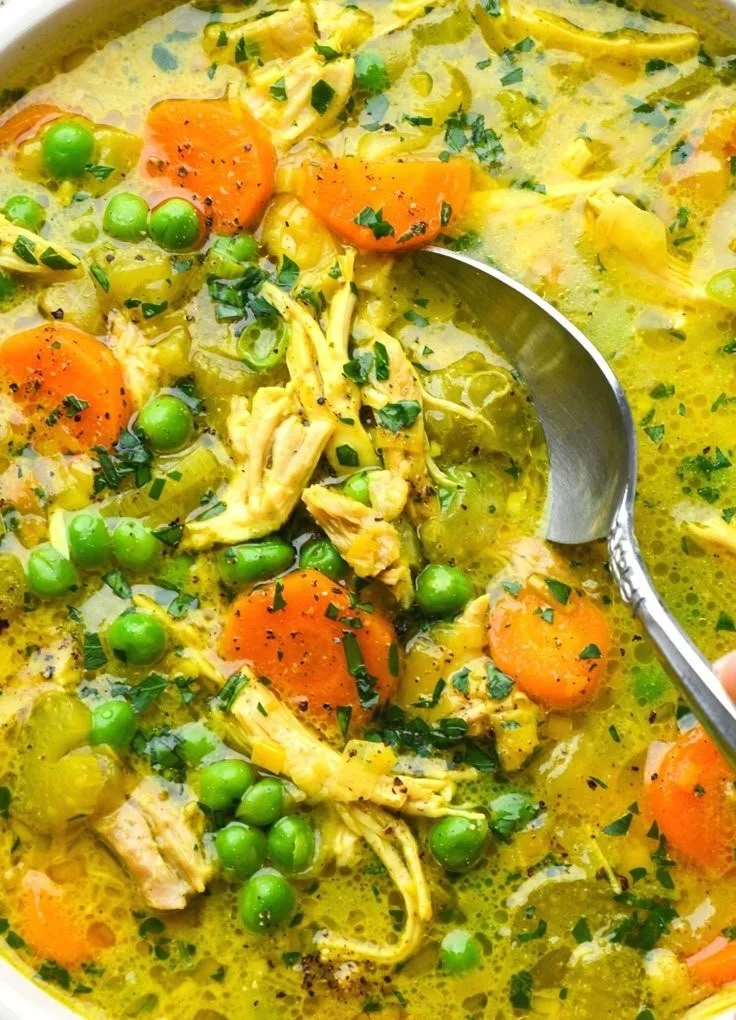 Bowl of anti-inflammatory turmeric chicken soup garnished with herbs