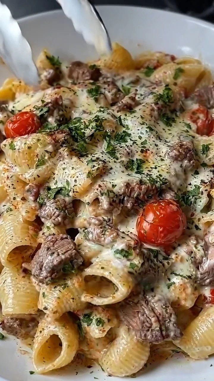 Creamy steak shells garnished with cherry tomatoes and fresh herbs