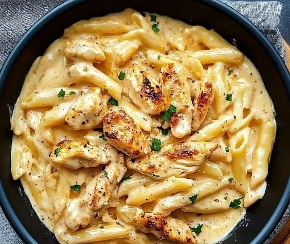 A bowl of Crock Pot Creamy Cajun Chicken Pasta topped with fresh herbs.