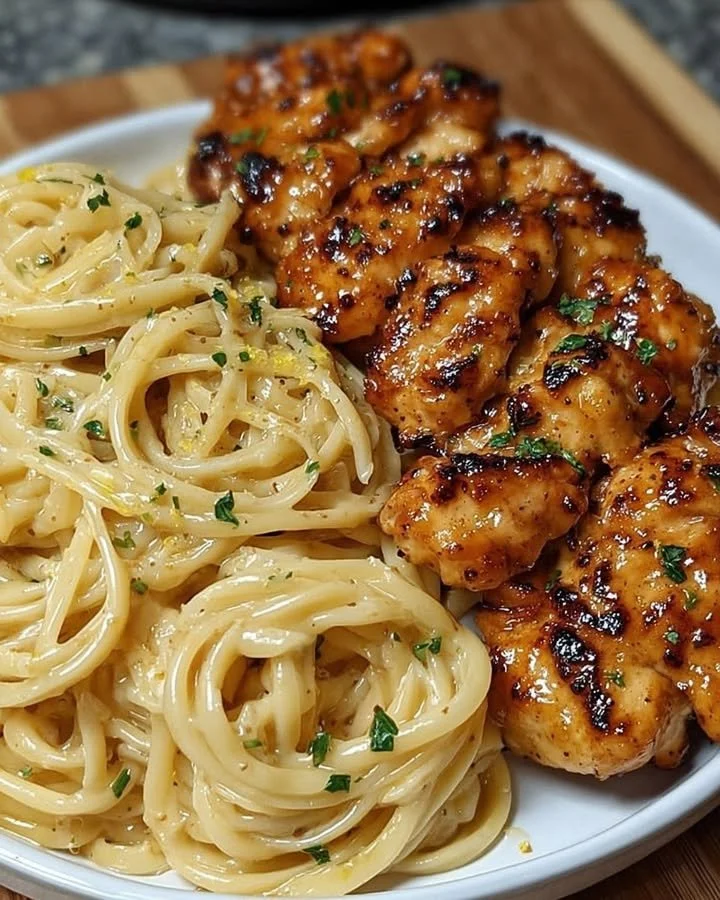 Lemon garlic butter chicken served over creamy parmesan pasta in a bowl