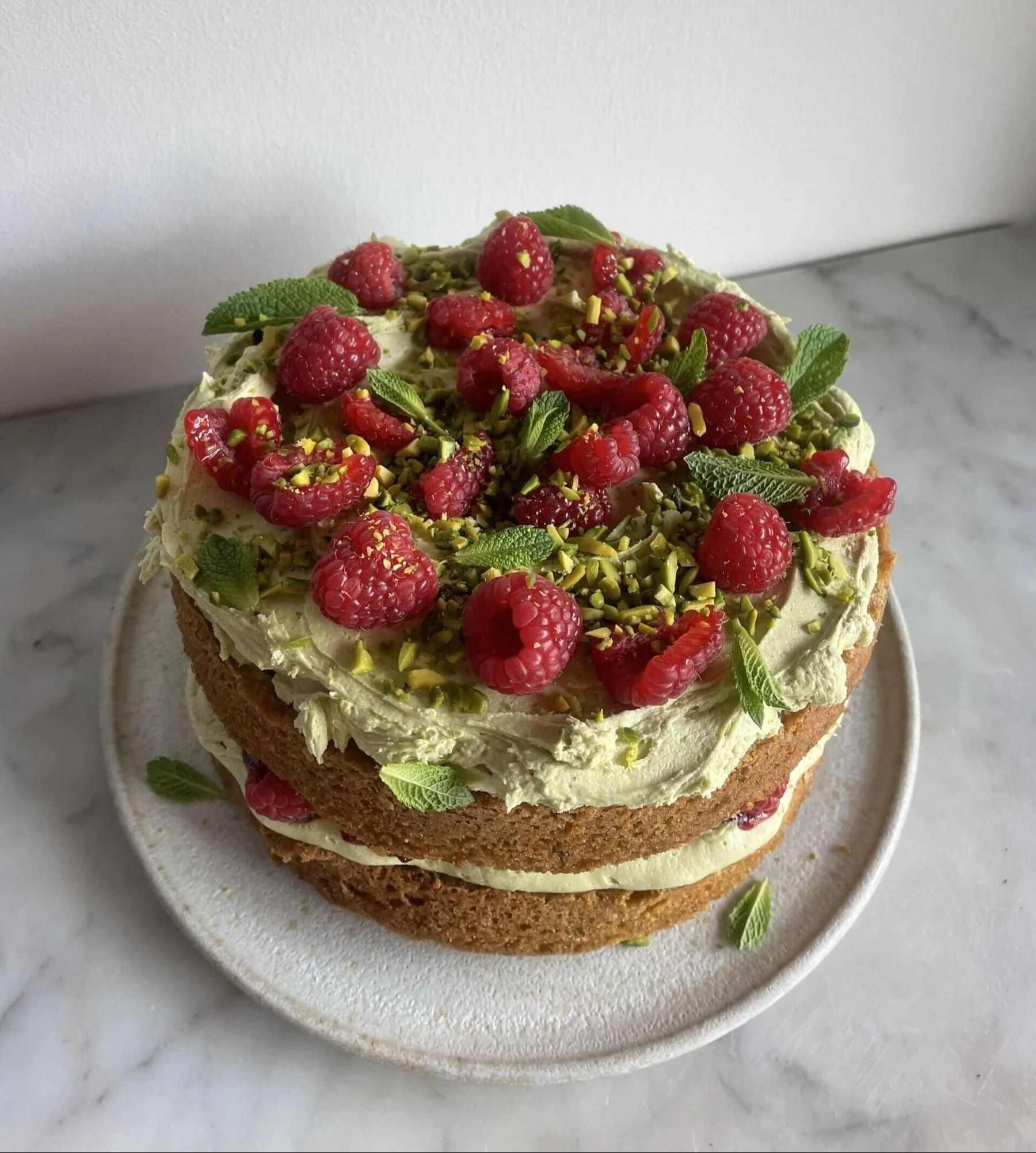 Delicious Pistachio Raspberry Cake with fresh raspberries and pistachio garnish.