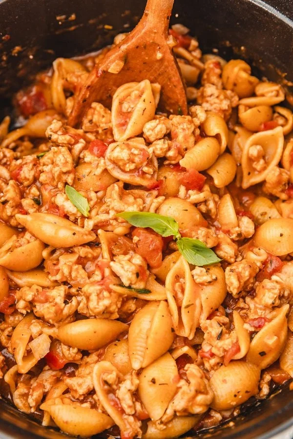 A plate of Chicken Pasta with rich tomato sauce garnished with herbs.