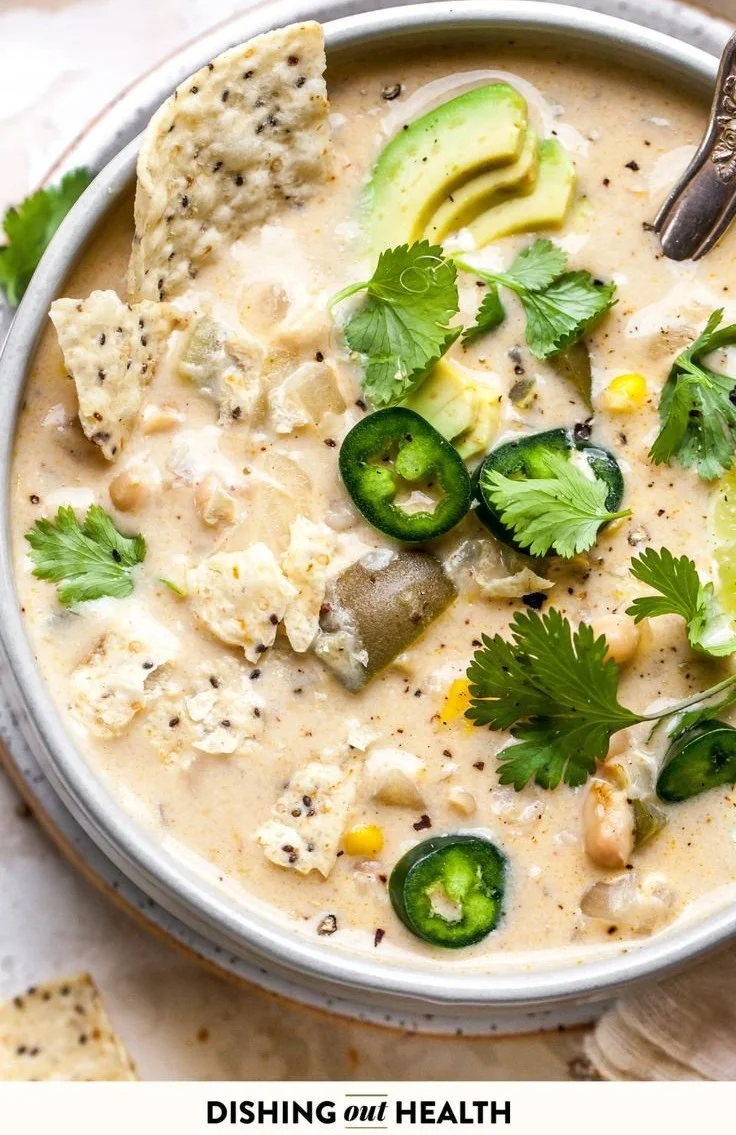 Bowl of creamy white bean enchilada soup with toppings of cilantro and avocado
