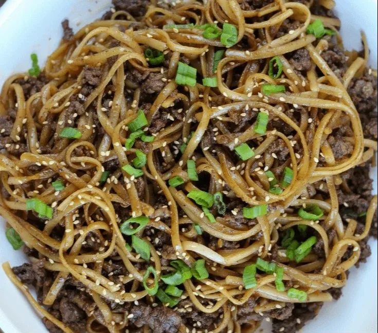 Bowl of easy Mongolian ground beef noodles with vegetables and herbs