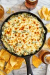 Hot spinach and artichoke dip served in a bowl with tortilla chips