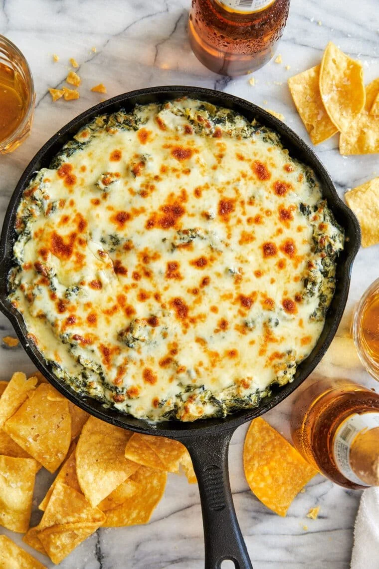 Hot spinach and artichoke dip served in a bowl with tortilla chips