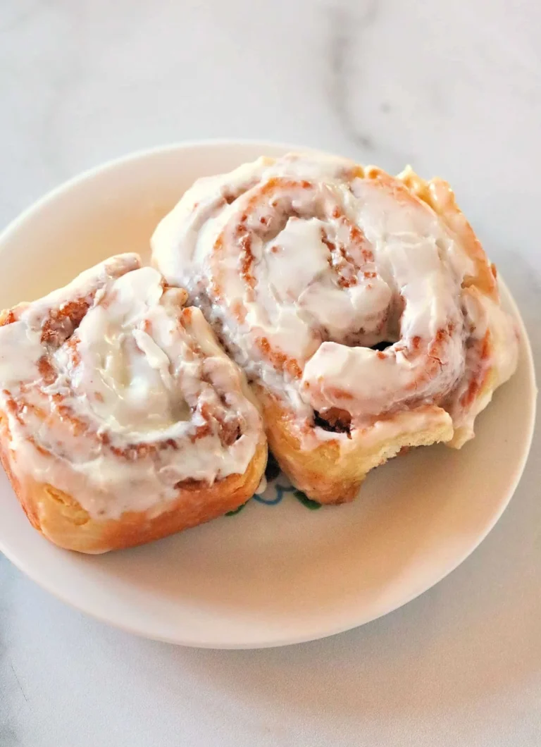 Fluffy cinnamon rolls topped with icing on a wooden table
