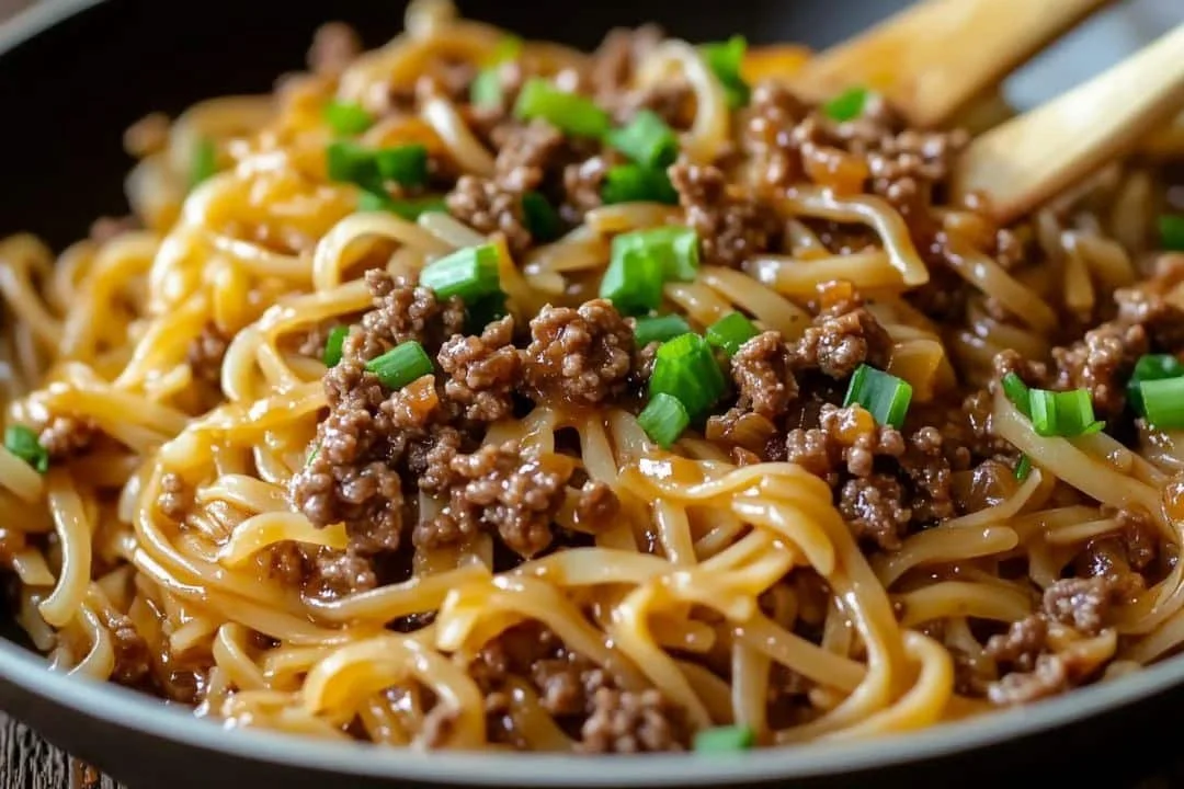 Mongolian ground beef noodles served in a bowl with fresh herbs.