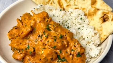 Delicious plate of homemade butter chicken with rice and herbs
