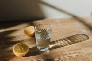 Baking soda recipe for weight loss: a glass of water with lemon halves on a wooden table